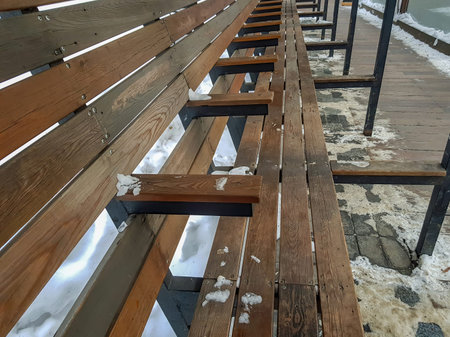 Snow-covered wooden bench in winter city park