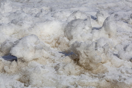 Textured surface of dirty melting snow with ground and soilの写真素材