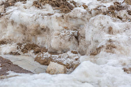 Textured surface of dirty melting snow with ground and soilの写真素材