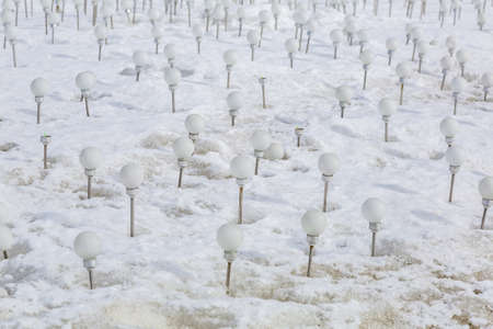 Eco-friendly energy-saving white solar-powered light bulbs on dirty melting snowの写真素材