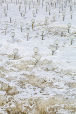 Eco-friendly energy-saving white solar-powered light bulbs on dirty melting snowの写真素材
