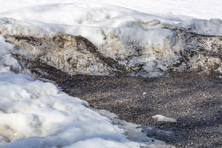 Textured surface of dirty melting snow with ground and soilの写真素材