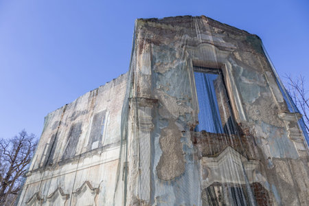 Part of the ruined facade of an abandoned old stone building at daytime