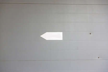 White sign on a dirty gray wall indicating left movementの写真素材