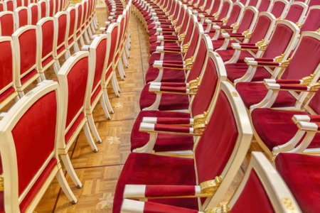 Comfortable wooden armchairs with red velvet in the theater hall for performances. Part of the auditorium without peopleの写真素材