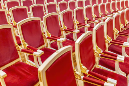 Comfortable wooden armchairs with red velvet in the theater hall for performances. Part of the...