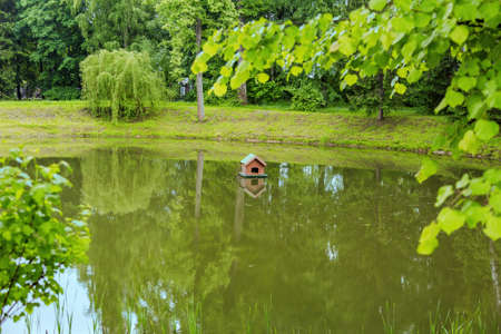 Small wooden house from boards for waterfowl birds on the surface of a picturesque pondの写真素材