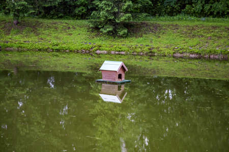Small wooden house from boards for waterfowl birds on the surface of a picturesque pondの写真素材