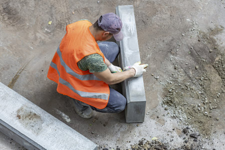 Handyman in an orange vest. Preparatory work for the installation of street curbstone