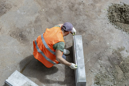 Handyman in an orange vest. Preparatory work for the installation of street curbstone