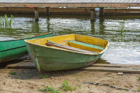 Empty shabby plastic boat for river walks stands on the shore of the pond