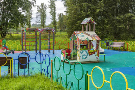 A multi-colored playground without people in a public city park among trees and summer greeneryの写真素材