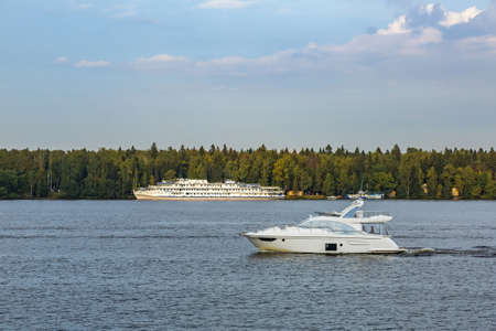 White three-deck ship on a river cruise. The vessel is moored by the green forestの写真素材