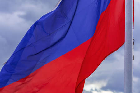 The tricolor state flag of Russia on a cloudy sky backgroundの写真素材