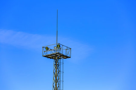 Old high radar tower against a bright blue sky