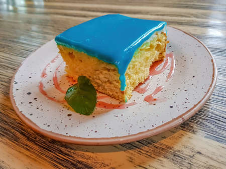 Freshly baked sponge cake with cream and mint leaf on a table in a cafeの写真素材