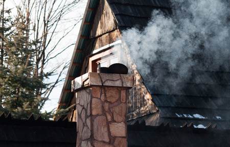 White smoke comes out of a house's chimney on a winter dayの写真素材