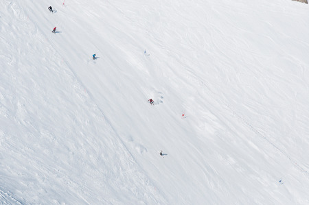 Skiers and snowboarders going down the slope at ski resortの写真素材