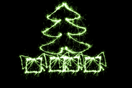 green Christmas tree and gifts made by sparkler on a black backgroundの写真素材