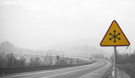 snowy road with frozen sign in winter, black and white with yellow alarm signの写真素材