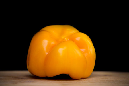 close up on yellow paprika on wood, black background