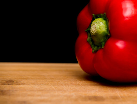 close up on red paprika on wood, black background