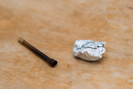 Marijuana in tin foil with pipe on wooden tableの写真素材