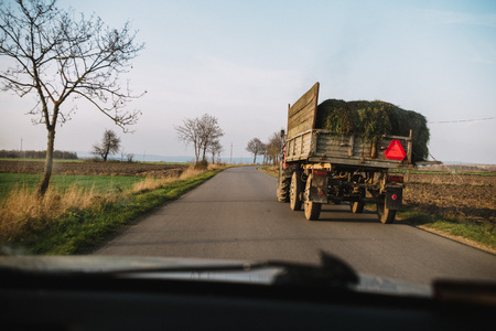 Danger in the road. tractor with grass on the street, view from the carの写真素材