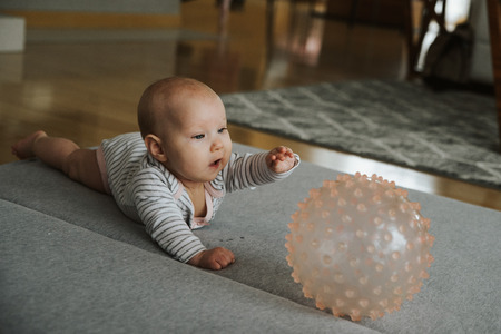newborn girl plays with a ball on the floorの写真素材