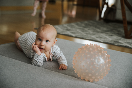 newborn girl plays with a ball on the floorの写真素材