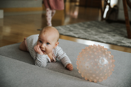 newborn girl plays with a ball on the floorの写真素材