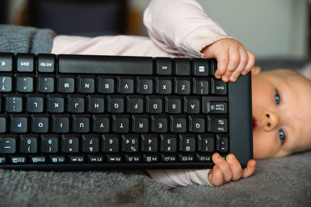 small child, first steps on the internet, a newborn baby is holding a keyboard from the computer