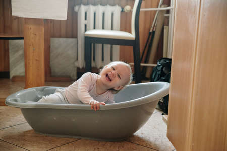 baby girl with blue eyes and blond standing in her bedの写真素材