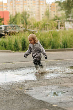 the girl is playing in the puddle in rubber bootsの写真素材