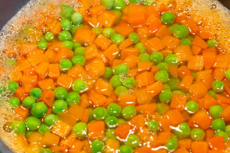 peas and carrots are cooked in a pot on an induction hobの写真素材
