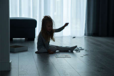 little girl is putting puzzles on the floor in the living roomの写真素材