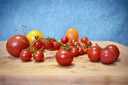 Fresh yellow and red cherry tomatoes on the wooden board and blue background, Selective Soft focusの写真素材
