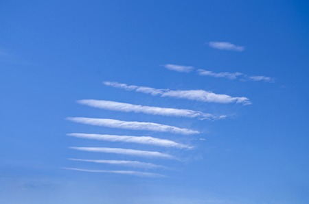 strange white clouds traces on blue skyの写真素材