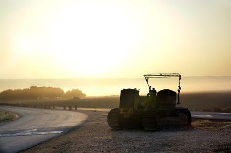 tractor ploughs the field in the early morning                 の写真素材