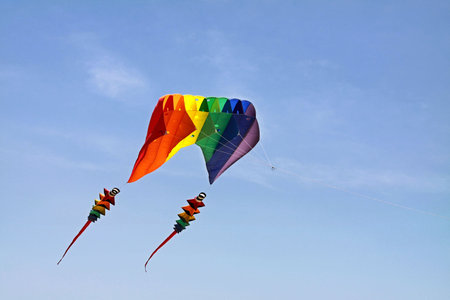 Colorful kite with two tails flying in the blue skyの写真素材