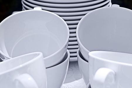 White ceramic cups and saucers on a white clothの写真素材