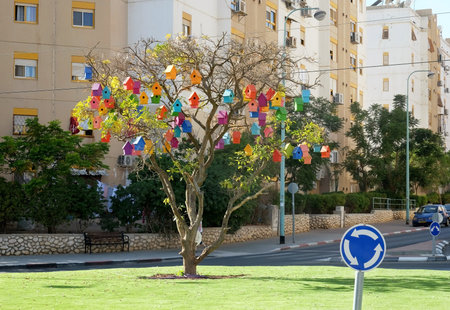 BEER SHEVA, ISRAEL - NOVEMBER 17, 2017: Multicolored birdhouses hang on a tree in the city at a roundaboutのeditorial素材