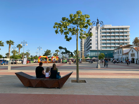 LARNAKA, CYPRUS - MAY 11, 2019: Family sitting on a bench on the promenade Phinikoudes near the seaのeditorial素材
