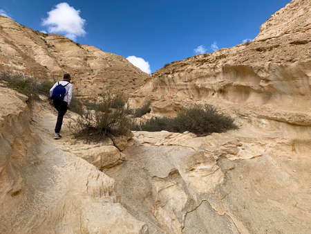 Tourist walks along hiking trail through Wadi Hawarim - a dry bed in the mountains in the middle of the Negev Desertの写真素材