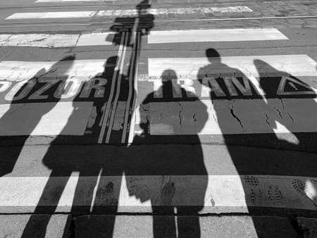 Shadows of people at the crosswalk. Inscription: Attention, tramの写真素材