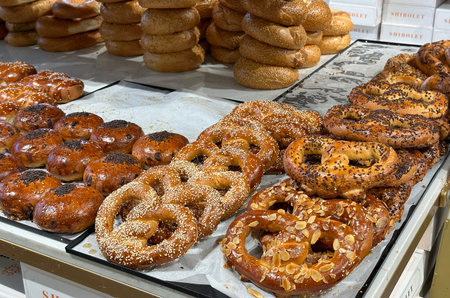 Bagels and buns sprinkled with sesame and almonds on the counter of a pastry shopの写真素材