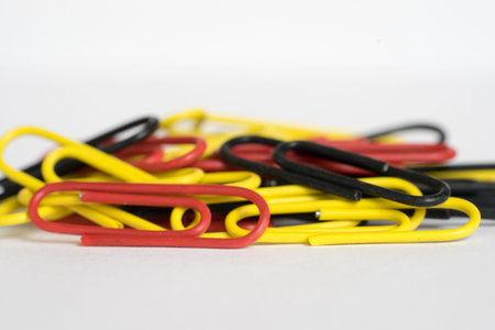Heap of yellow, red and black paper clips on white backgroundの写真素材