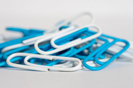 Heap of blue and white paper clips on white background