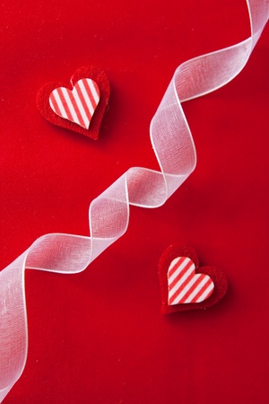 Two hearts made of felt with a red backgroundの写真素材