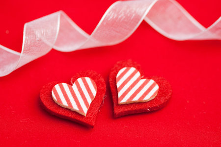 Two hearts made of felt with a red background
